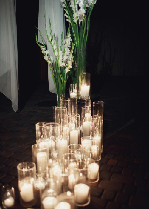 Candles burn standing in tall vases on the floor